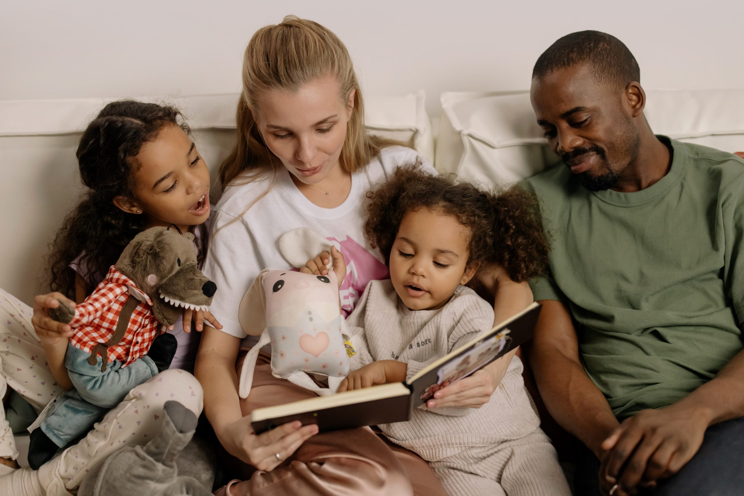 Family sitting on a couch reading together with puppets.
