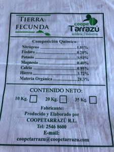 A fertilizer label with three boxes outlined in black on a white background. The top box says "Tierra Fecunda" and "coope Tarrazu". The middle box says "Composicion Quimica:" followed by a list of chemical compositions. The list states: Nitrogeno, 1.81%; Fosforo, 0.20%; Potasio, 3.52%; Magnesia, 0.40%; Calcio, 0.95%; Hierro, 3.72%; Materia Organica, 28.3%. The bottom box has a header that reads: "Contenido Neto:". Below the header are three small boxes equally spaces apart label 10 Kg., 20 Kg., and 35 Kg., left to right. Underneath the boxes it states "Fabricante:", followed by "Producido y Elaborado por COOPETARRAZU R. L.". This is succeeded by "Tel: 2546 8600" and "E-mail: coopetarrazu@coppetarrazu.com".