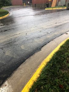 Sediment in water flowing down a road with yellow curb.