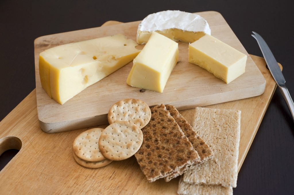 Cheese platter with an assortment of cheeses served with water biscuits and crackers on a dark background