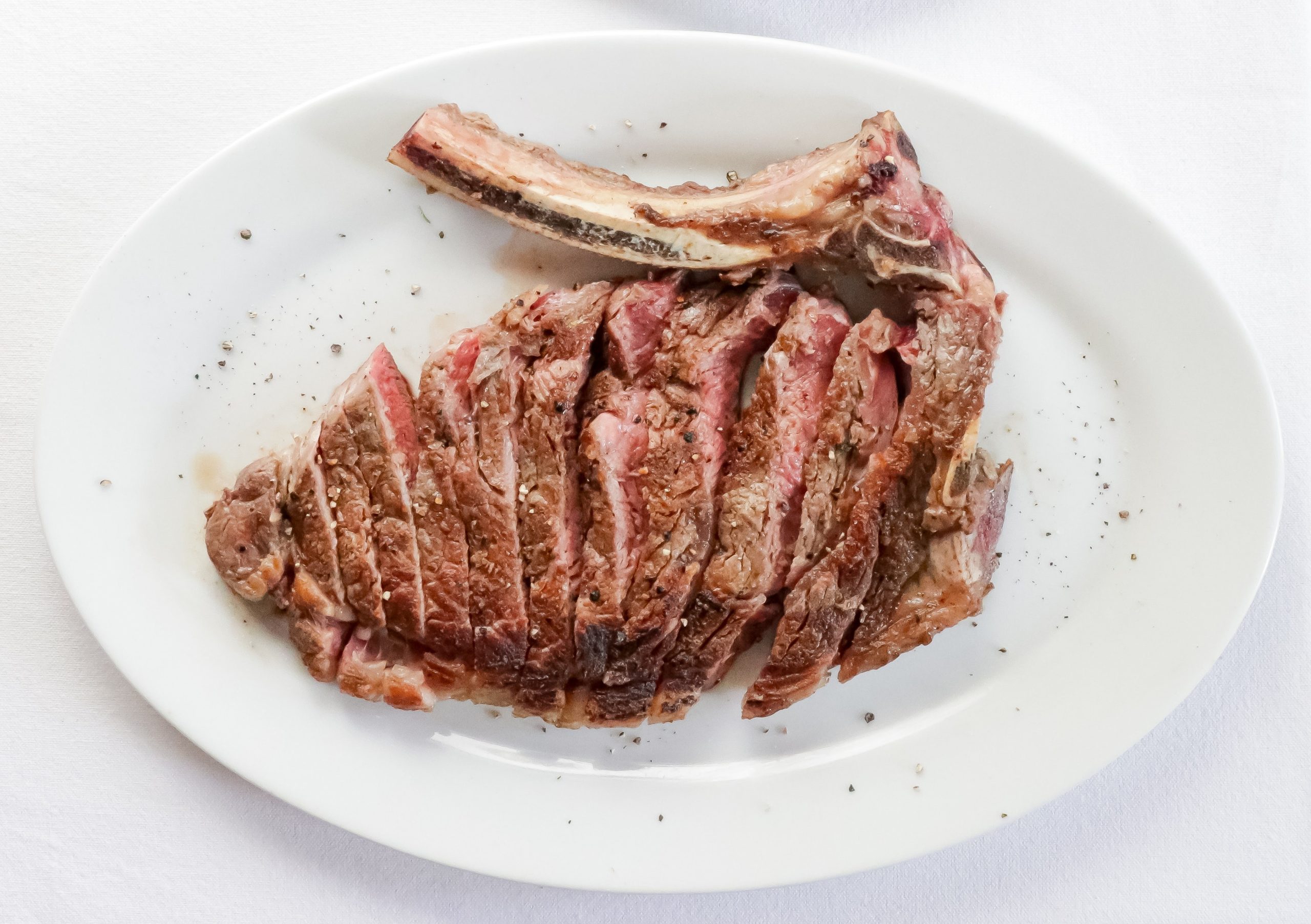 A medium rare steak on a plate cut into strips