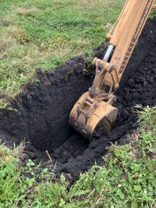 Backhoe digging pit with four feet of black soil