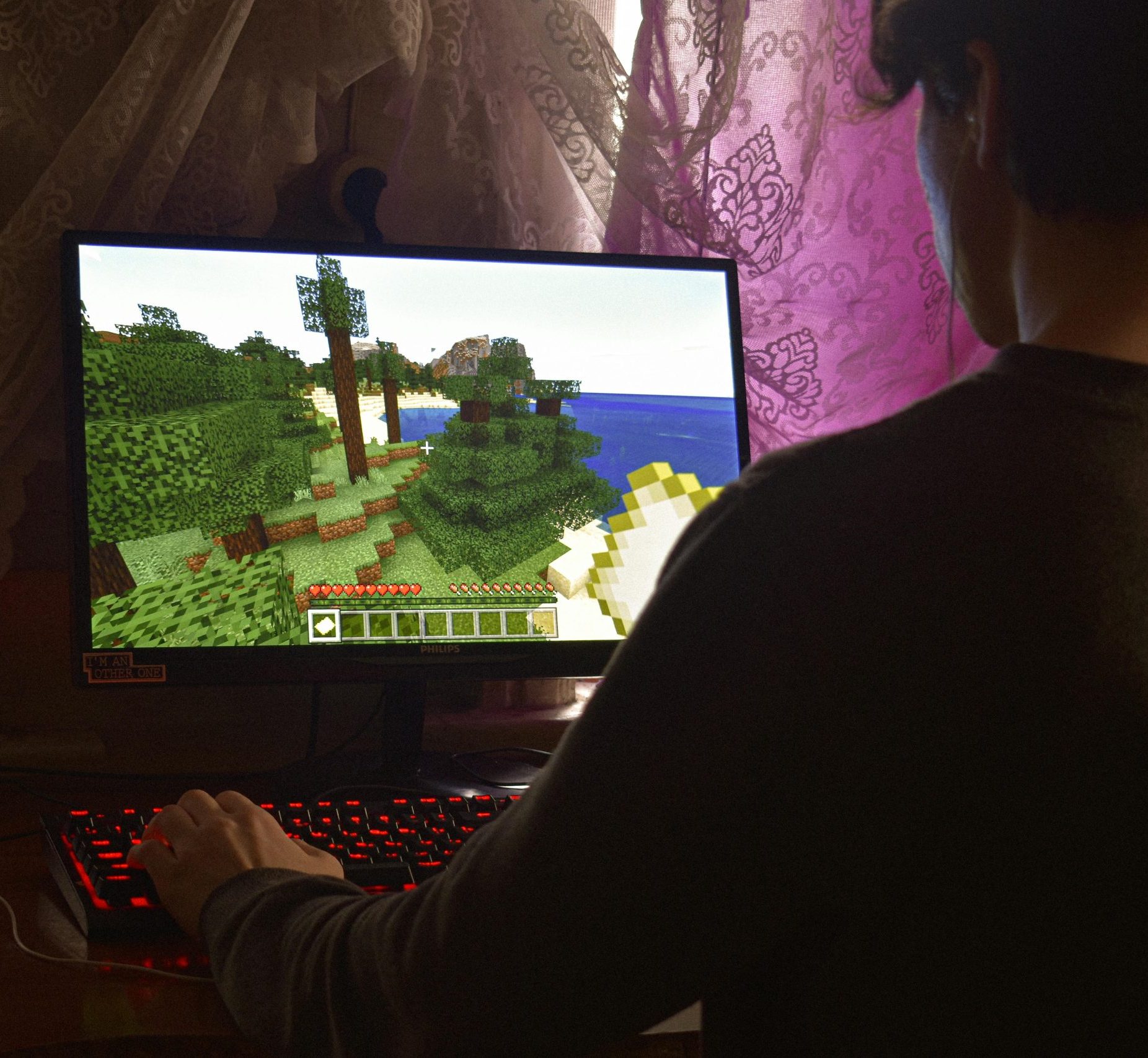 A person seated at a desktop playing Minecraft.