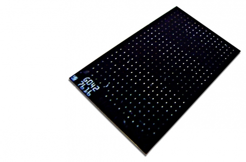 A photo of a black, flat chip with many holes in the top.