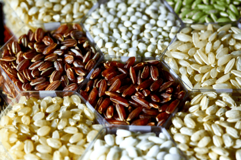 A photo displaying the variety of color (red, light red, white, green, yellow, cream) and shape (round, short, and long ) of rice grains.