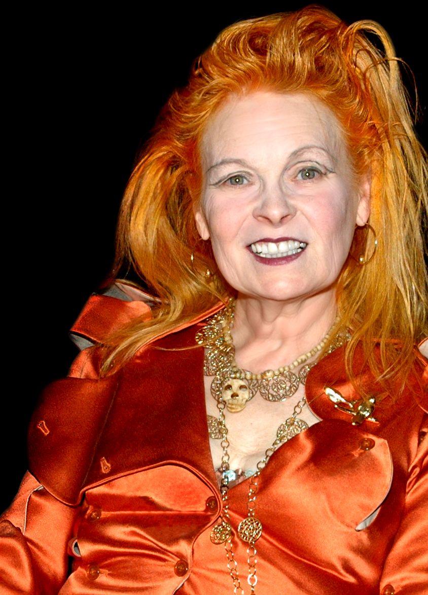 A portrait of fashion designer Vivienne Westwood with vibrant orange hair wearing a gold necklace, exuding elegance and confidence.