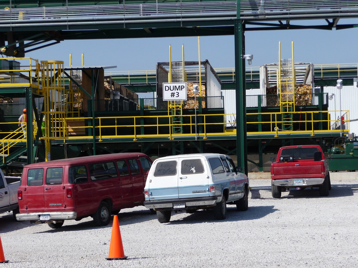 A parking lot with a factory beyond it.